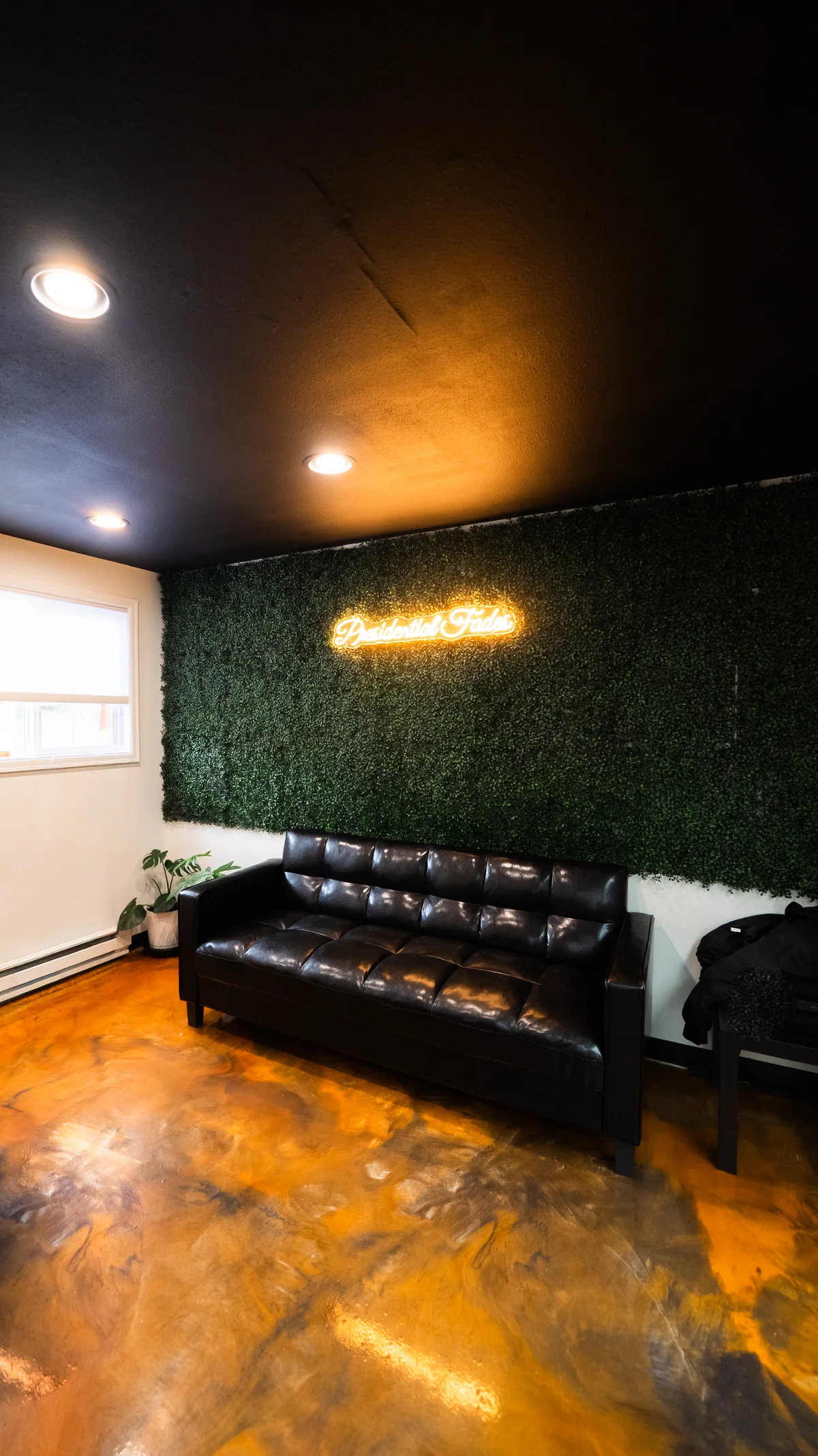 Waiting area with leather couch and neon sign at Presidential Fades